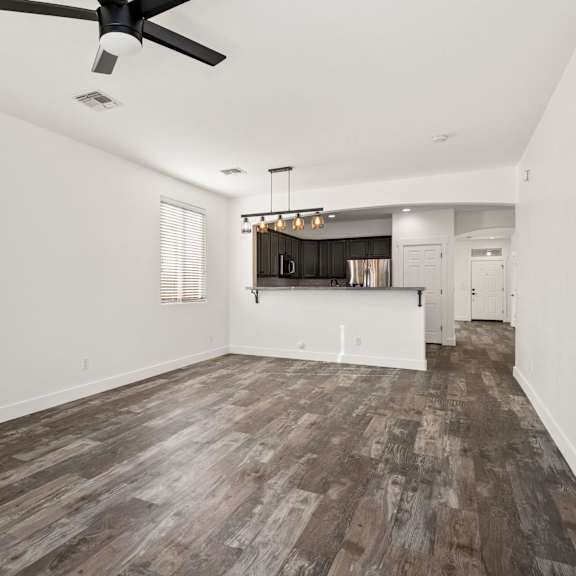 a room with a ceiling fan and wooden flooring.