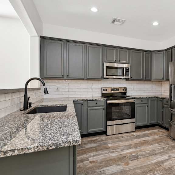 a kitchen with a refrigerator, oven, and microwave.