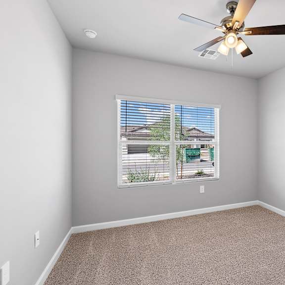 a room with a ceiling fan and a window with blinds.