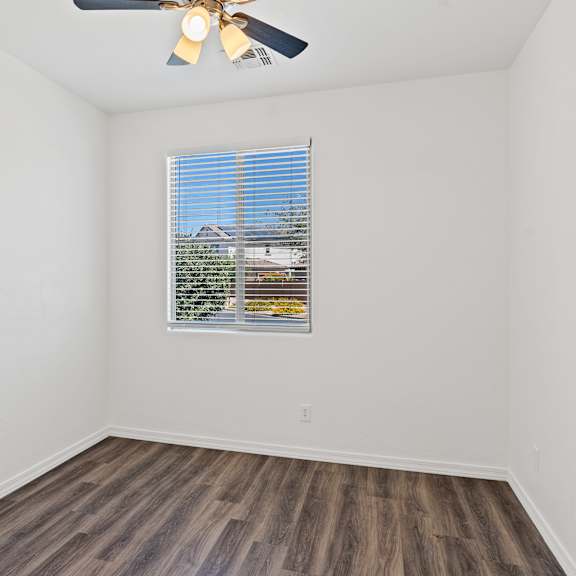 a room with a ceiling fan and a window with blinds.