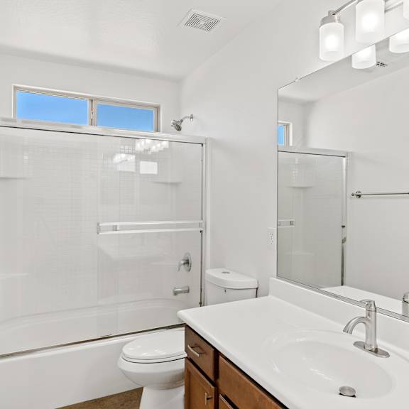 a white bathroom with a toilet, sink, and shower.
