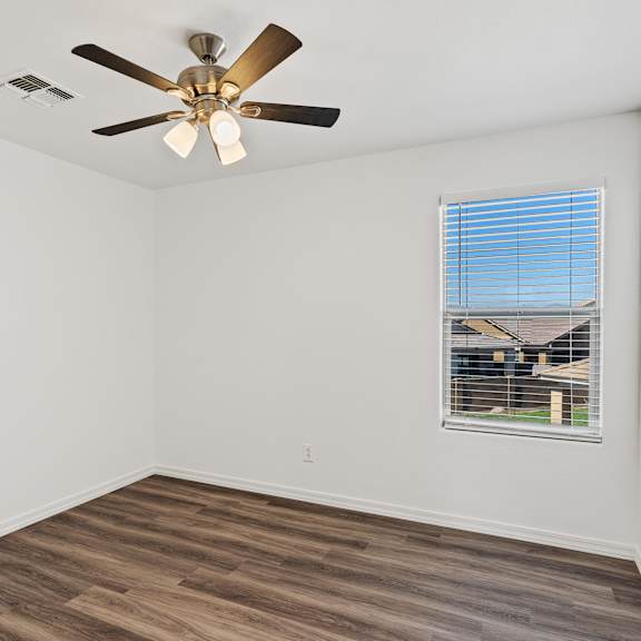 a room with a ceiling fan and a window with blinds.