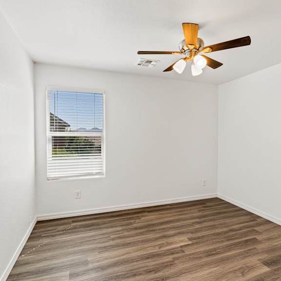 a room with a ceiling fan and a window with blinds.