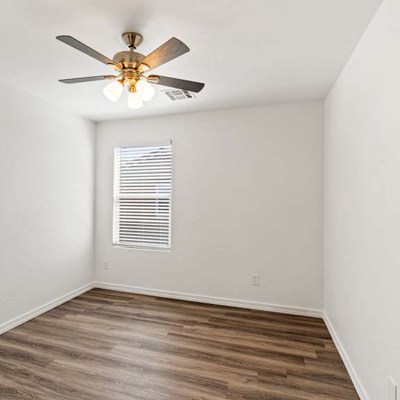 a room with a ceiling fan and a window with blinds.