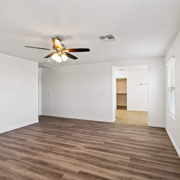 a room with a ceiling fan and wooden flooring.