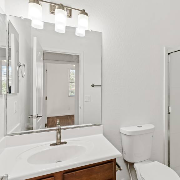 a white bathroom with a sink, toilet, and shower.