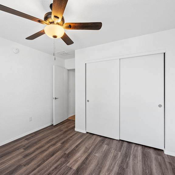 a living room with white walls and a ceiling fan
