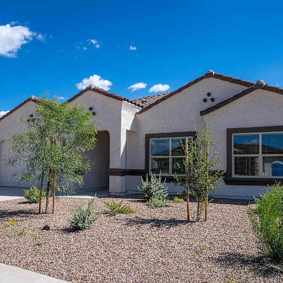 a modern house with a gravel driveway and a few trees.
