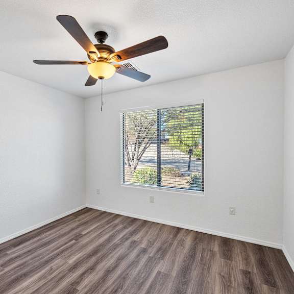 an empty living room with a ceiling fan and a window
