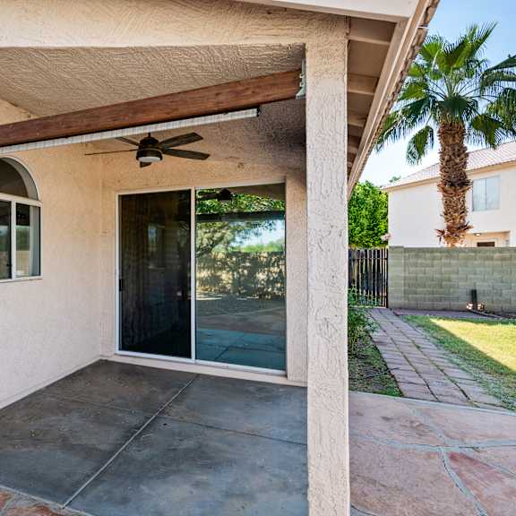 a patio area with a sliding glass door and a ceiling fan.