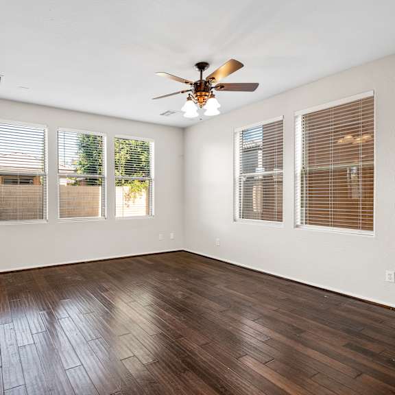 a room with a ceiling fan and wooden flooring.