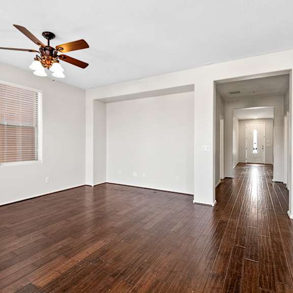 a room with a ceiling fan and wooden floors.