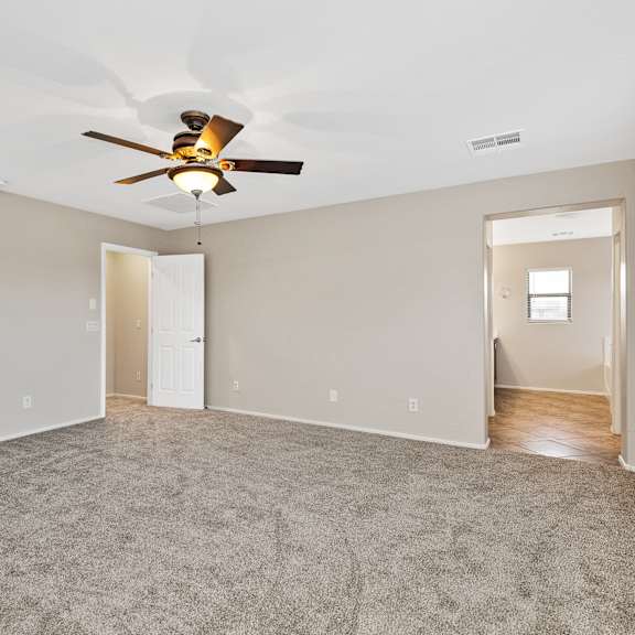 a spacious room with a ceiling fan and carpeted floor.