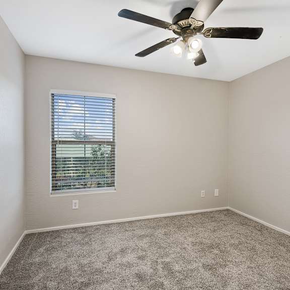 a room with a ceiling fan and a window with blinds.