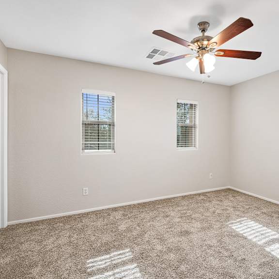 a room with a ceiling fan and carpeted floor.