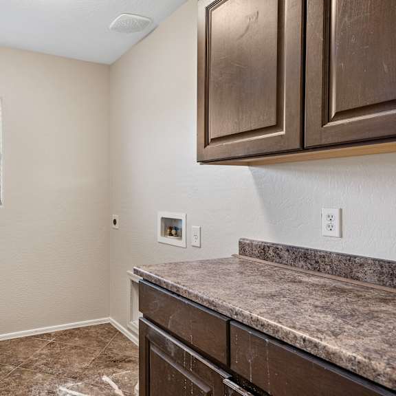 a kitchen with brown cabinets and a marble countertop.