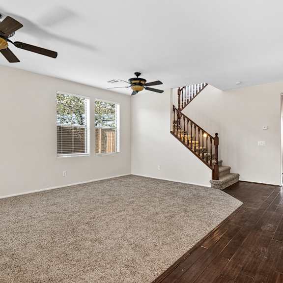 a spacious room with a staircase and two ceiling fans.