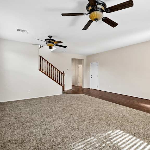 a room with a carpeted floor and a ceiling fan.