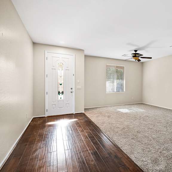 a room with a white door, carpeted floor, and a ceiling fan.