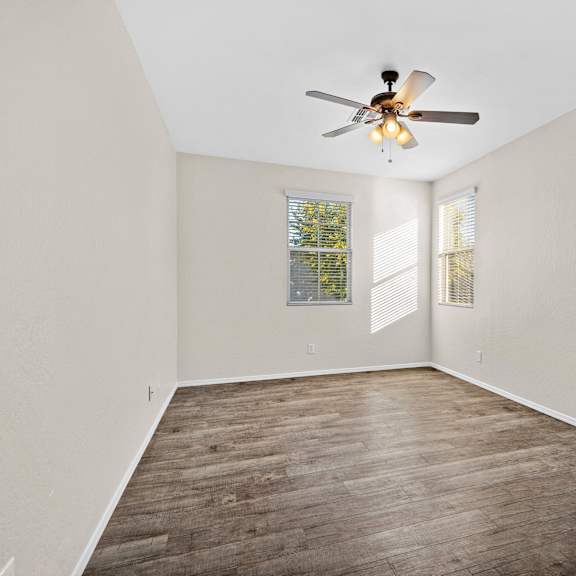 an empty living room with a ceiling fan and a window