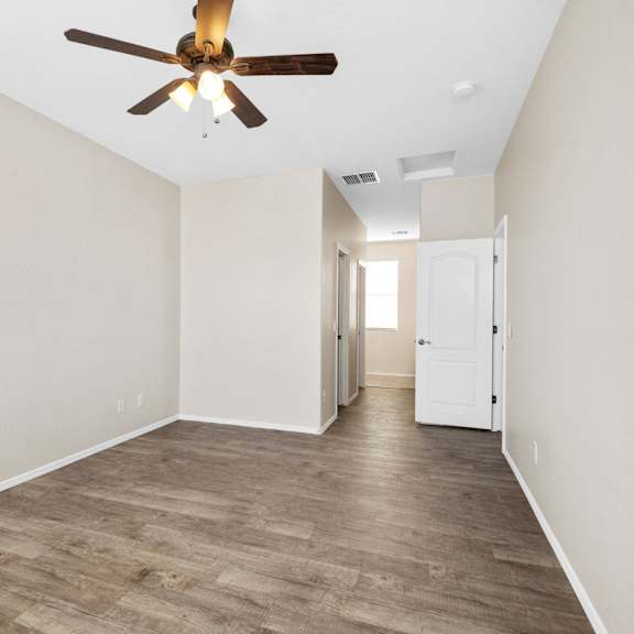 an empty living room with a ceiling fan and white walls