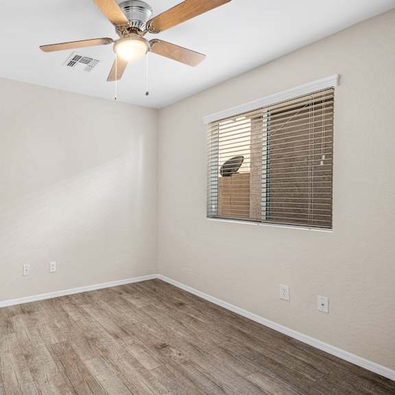 an empty room with a ceiling fan and a window