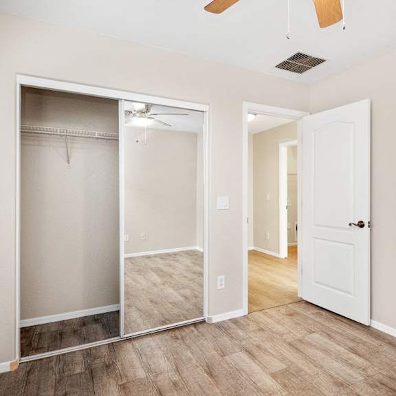 an empty bedroom with a closet and a mirrored closet door