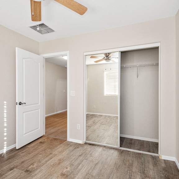 an empty bedroom with a closet and a ceiling fan