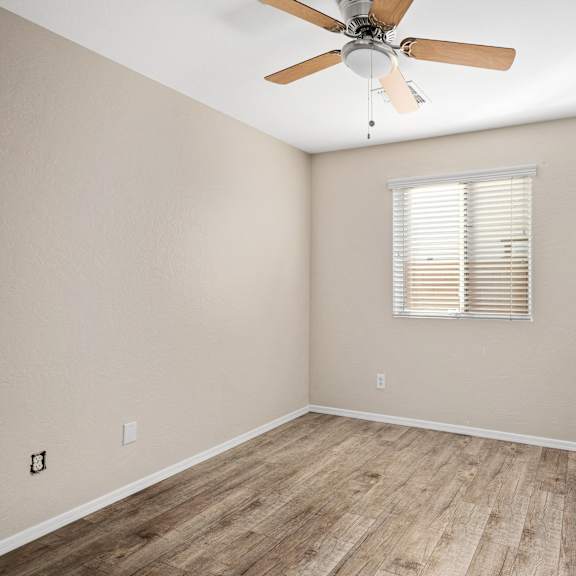 an empty room with a ceiling fan and a window
