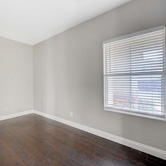 an empty living room with wood floors and a large window