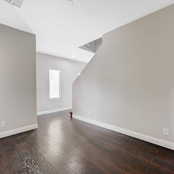 an empty living room with a hard wood floor and white walls