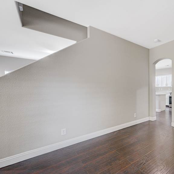 an empty living room with a hard wood floor and a staircase