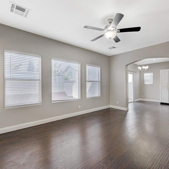 an empty living room with a ceiling fan and windows