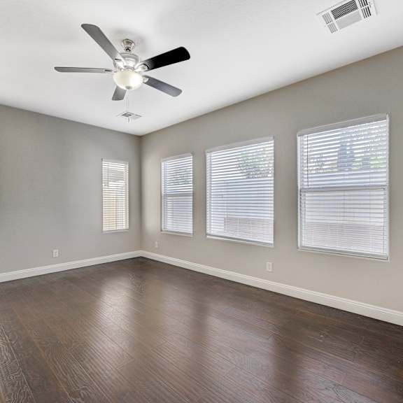 an empty living room with wood floors and a ceiling fan