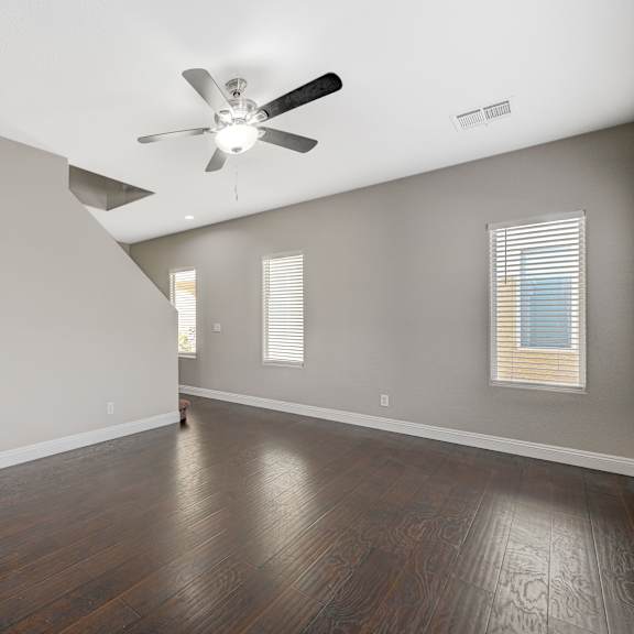 an empty living room with wood floors and a ceiling fan
