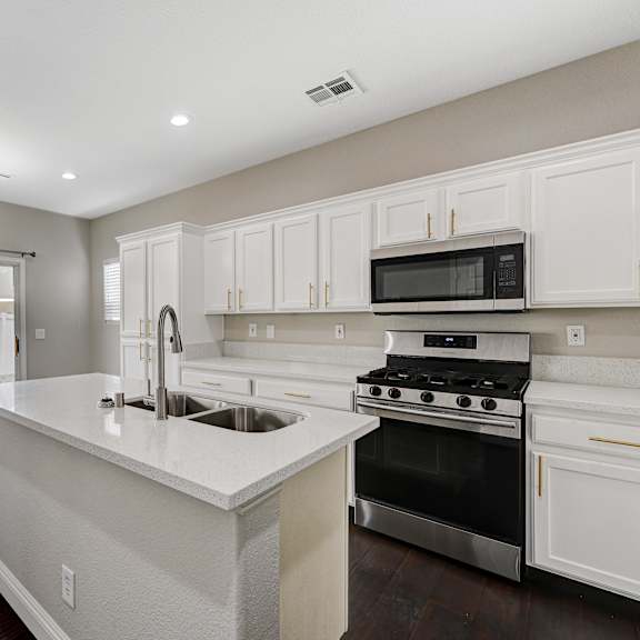 a large white kitchen with a large island and stainless steel appliances
