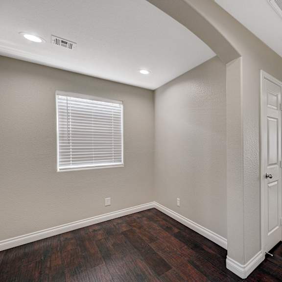 an empty living room with wood floors and a white door