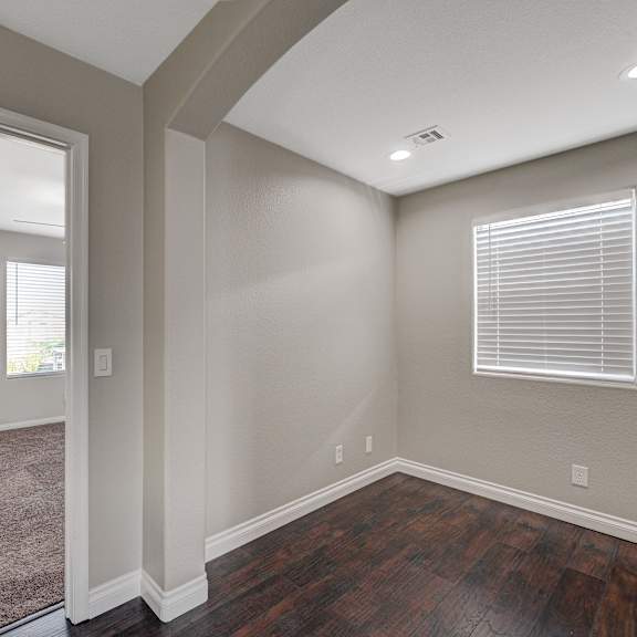 an empty living room with wood flooring and a window