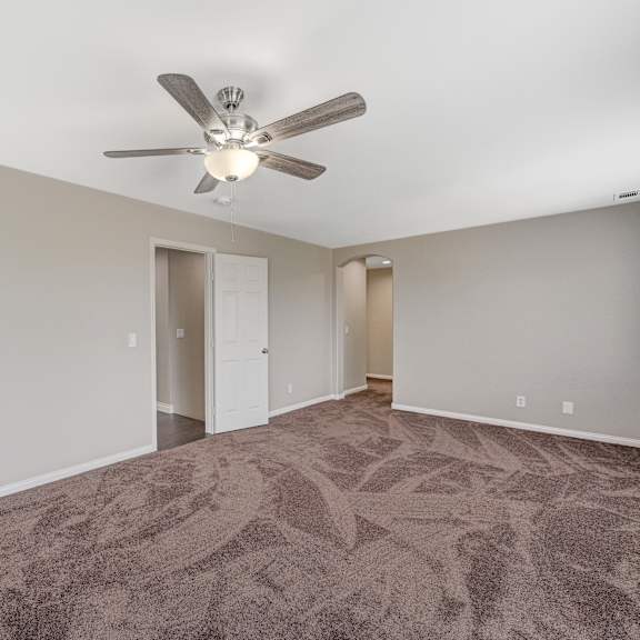 an empty living room with carpet and a ceiling fan
