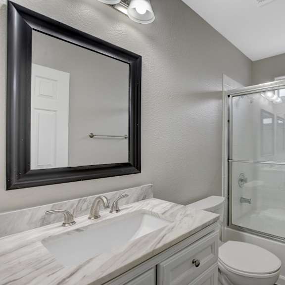 a bathroom with a sink, toilet, and shower.