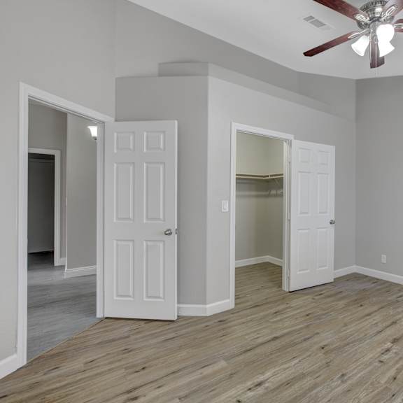 a room with a ceiling fan and wooden flooring.