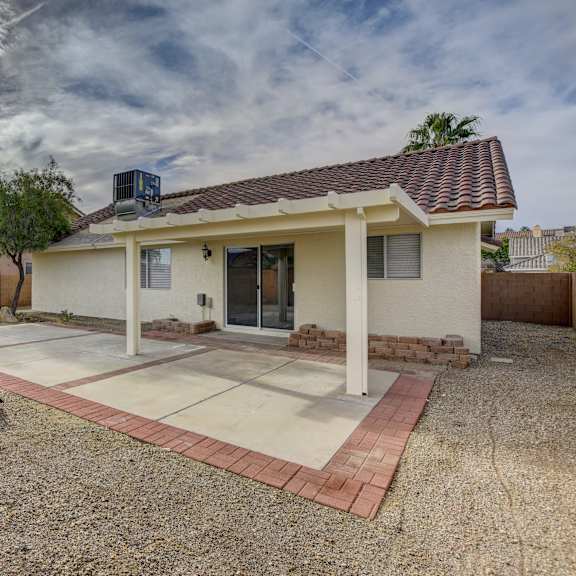 a house with a gravel driveway and a tree in front.