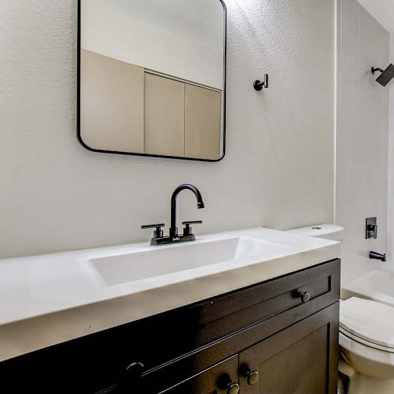 a bathroom with a sink, mirror, toilet and bathtub.