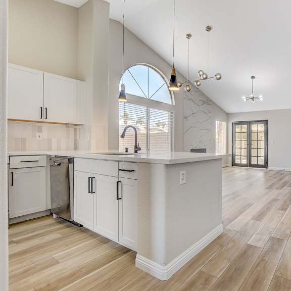 a kitchen with white cabinets and a wooden floor.