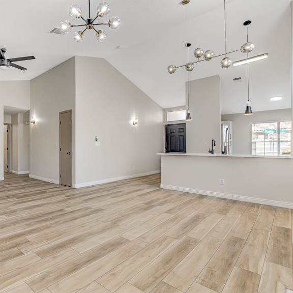 a spacious room with wooden flooring and a ceiling fan.