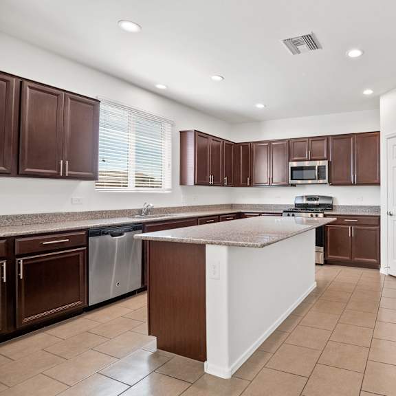 a kitchen with brown cabinets and a stainless steel refrigerator
