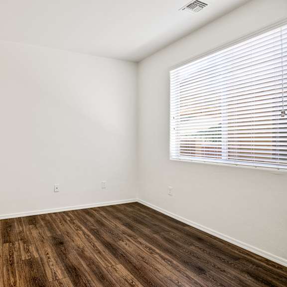an empty room with wood flooring and a large window