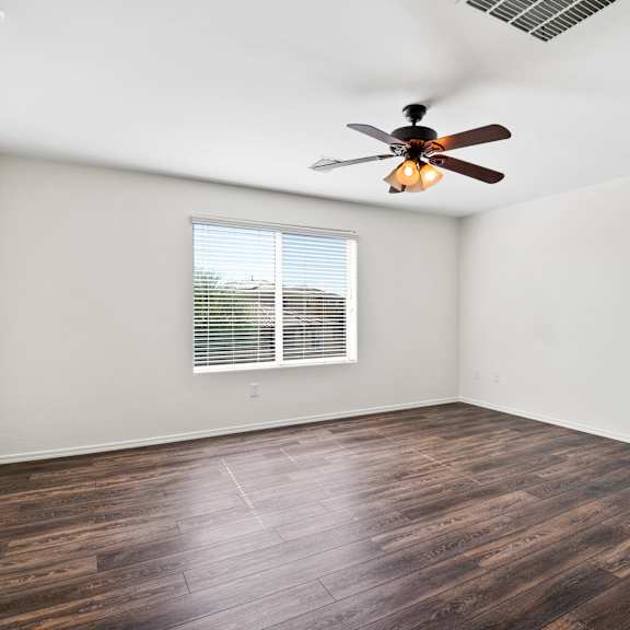 an empty living room with a ceiling fan and a window
