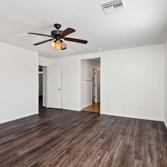 an empty living room with a ceiling fan and a window