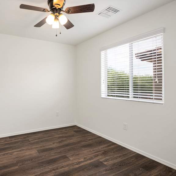 an empty room with a ceiling fan and a window